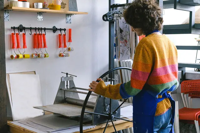 Side view of anonymous female master working at workbench with printing press with wheel in modern art studio with rollers. How to Dispose of Printmaking Chemicals in Canada