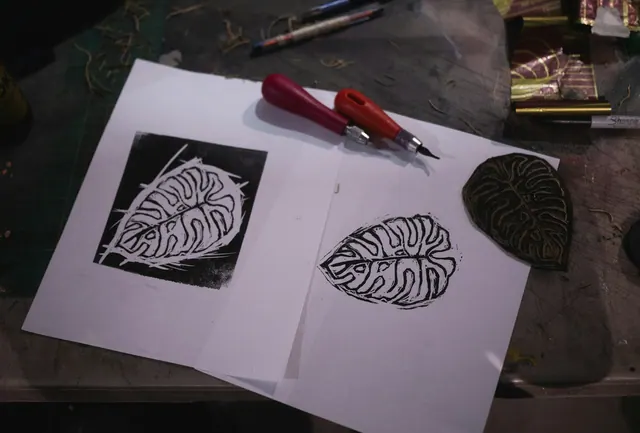 A linocut print of a leaf beside a carving tool on paper. Linocut Reduction Prints, Step by Step: Many Colors from a Single Block
