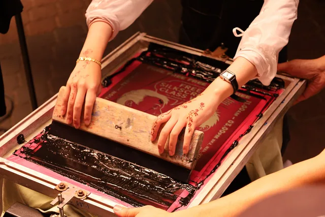 A serigrapher demonstrating screen painting by pulling the squeegee to create a design at the TEDxUTM Conference in Johor Bahru, Malaysia on 25 May 2025. Vinyl Stencil Screen Printing on Fabric: A Beginner's First Project